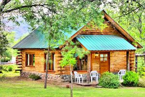 a log cabin with two white chairs and a blue roof at casas del milagro in Villa General Belgrano