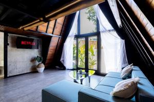 a living room with a blue couch and large windows at Brisa Lofts Uluwatu in Uluwatu