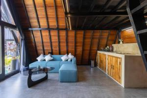 a living room with a blue couch and a table at Brisa Lofts Uluwatu in Uluwatu