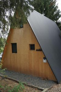 a large wooden building with a metal roof at Patak Kuckó cabin ház in Szőce