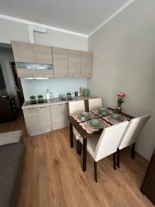 a dining room table with white chairs and a kitchen at JULA Pokoje Blisko Plaży, Dąbki in Dąbki
