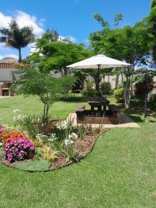 a park with a bench and an umbrella and flowers at The Ridge BnB in Manzini