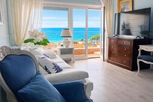 a living room with a couch and a television and the ocean at Due Passi dal Cielo Apartment Piscina Condominiale fino al 30 Agosto in Anzio