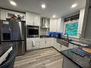 a kitchen with white cabinets and a stainless steel refrigerator at Super Comfy 3 BR Home Sleeps 8 in Doraville