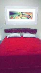 a red bed with two pillows and a painting on the wall at Villa Rossy in Samaipata
