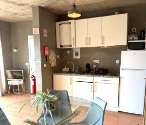 a kitchen with white cabinets and a glass table at Porto Santo Balcony View House in Porto Santo