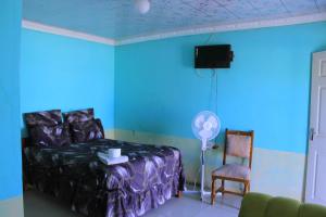 a blue room with a bed and a chair and a fan at Equatorial Guest House in Rustenburg +149 photos