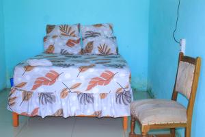a bed in a room with a blue wall and a chair at Equatorial Guest House in Rustenburg