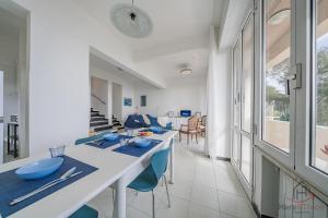 a kitchen and dining room with a long table and blue chairs at Sea Dream - Vista Mare - Giardino - Box Privato in Bergeggi