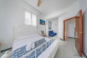 a white bedroom with a bed and a blue chair at Sea Dream - Vista Mare - Giardino - Box Privato in Bergeggi