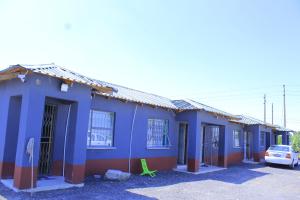 a blue building with a car parked in a parking lot at Equatorial Guest House in Rustenburg