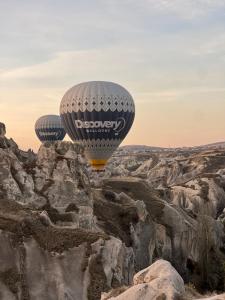 two hot air balloons flying over a rocky canyon at Hush Cappadocia Hotel in Ürgüp +27 photos