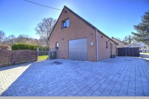 a brick building with a garage on a driveway at Villa 2 chambres in Trooz