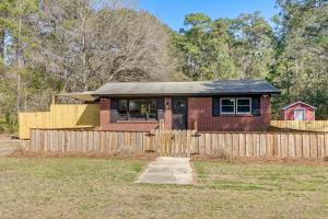 a small brick house with a wooden fence at Deck & Spacious Yard! Wilmington Gem on Half-Acre in Wilmington