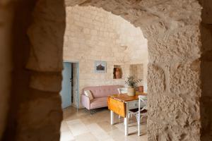 a living room with a table and a pink couch at Trullo Elisa in Monopoli