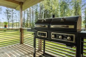 a grill on a deck with trees in the background at Orava Järven Talo in Ranua