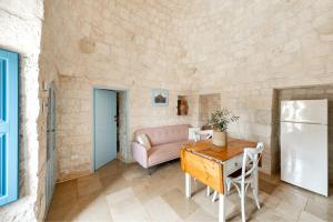 a living room with a pink couch and a table at Trullo Elisa in Monopoli +7 photos