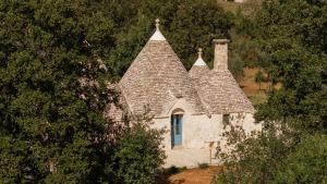 an old stone house with a roof with trees at Trullo Elisa in Monopoli