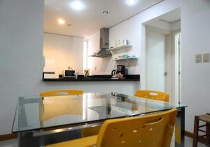 a kitchen with a glass table and yellow chairs at Zona shopping del Sol, Asunción in Asunción