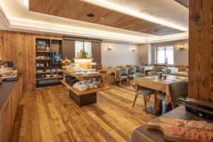a restaurant with wooden floors and tables and chairs at Negritella Sweet Hotel in Ziano di Fiemme