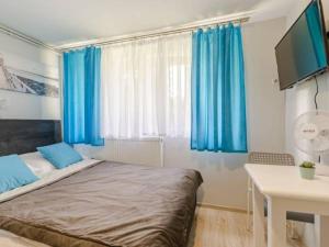 a bedroom with blue curtains and a bed and a desk at Spełniony sen in Stegna