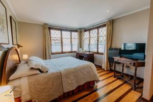 a bedroom with a bed and a desk and windows at Hotel Fundo Las Tortolas in Limache +77 photos