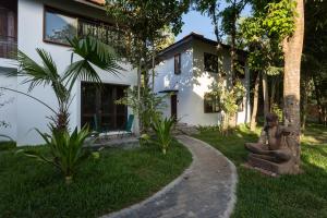 a statue sitting in the grass in front of a house at Sala Baï Hotel & Restaurant School in Siem Reap