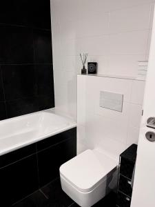 a white bathroom with a toilet and a bath tub at Studio Nuppu Comfort, AC in Trnávka
