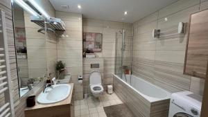 a bathroom with a toilet and a tub and a sink at DO Apartments in Druskininkai +28 photos