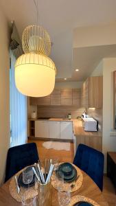 a kitchen with a table with chairs and a chandelier at DO Apartments in Druskininkai