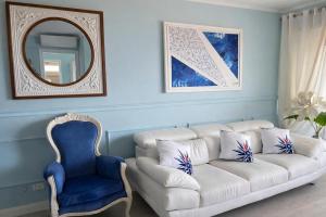 a living room with a white couch and a blue chair at Due Passi dal Cielo Apartment Piscina Condominiale fino al 30 Agosto in Anzio