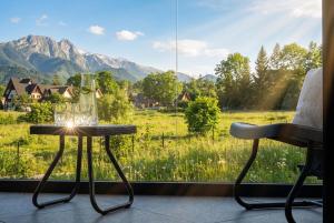 a table and chair in front of a window with a view at CHATAR Tatra Premium Suites in Zakopane