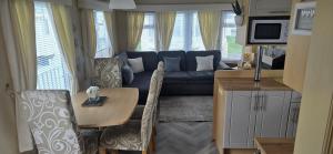 a living room with a blue couch and a table at Pcj caravan hire in Kinmel Bay