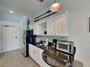 a kitchen with white cabinets and a black microwave at Inn at Seacrest #206 in Rosemary Beach