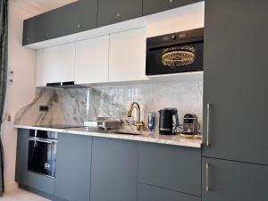 a kitchen with white cabinets and a sink and a microwave at Vert Unique Luxury Experience in Băile Felix in Baile Felix