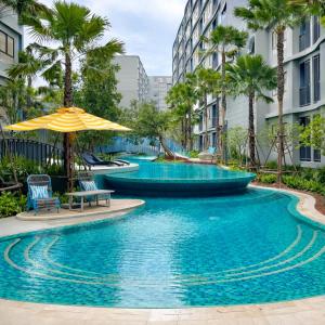 a pool with chairs and an umbrella and palm trees at Modern Apartment with Gym & Pool in Kathu