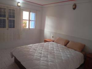 a bedroom with a white bed and a window at amazigh soul experience in Mirleft
