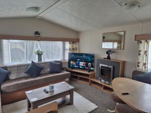 a living room with a couch and a television at Blanco's by the sea in Saint Osyth
