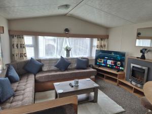a living room with a couch and a flat screen tv at Blanco's by the sea in Saint Osyth