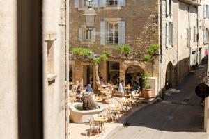 a street with tables and chairs and people sitting at tables at Le Moulin, Lourmarin, a Beaumier Hotel in Lourmarin