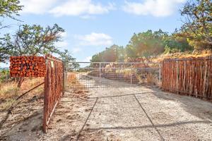 an open gate with a fence on a dirt road at Daybreak Ridge Sunrise Bluff in Blanco
