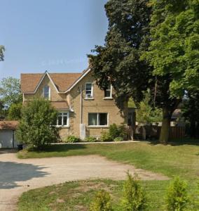 a house with a tree in front of a driveway at Walkerton Sauna Suite in Walkerton