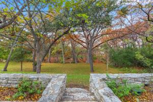 a stone wall in a park with trees at Cypress Moon in Wimberley