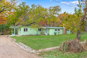 a green house in the middle of a yard at Cypress Moon in Wimberley