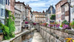 a canal in a city with buildings and flowers at La Halte Montbrisonnaise in Montbrison