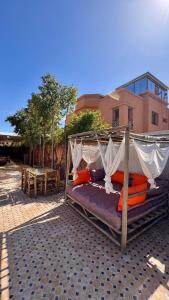 a canopy bed with orange pillows on a patio at Villa de prestige à Marrakech in Marrakesh