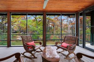 two chairs and a table on a porch with windows at Cypress Star in Wimberley