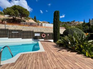 a swimming pool with a wooden deck and plants at Althaia Hills - Precioso adosado con terraza panorámica al mar y montaña in Altea