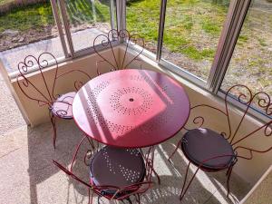 a pink table and chairs in front of a window at Le gîte d'Ouillon in Saint-Hostien