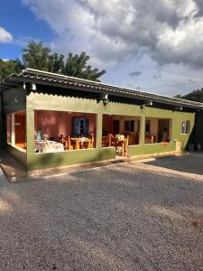 a green house with a patio and a table at Pousada Safari do Jaguar in Poconé